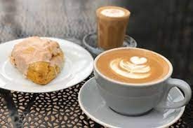 A plate with a scone next to a cofee cup